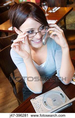 21 year old girl in restaurant talking on a mobile phone, with a mini DVD player View Large Photo Image Stock Image - 21 year old girl in restaurant talking on a mobile phone, with a mini DVD player. Fotosearch