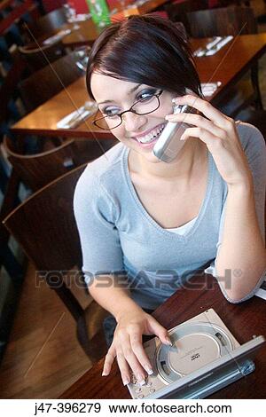 21 year old girl in restaurant talking on a mobile phone, with a mini DVD player View Large Photo Image Stock Photo - 21 year old girl in restaurant talking on a mobile phone, with a mini DVD player. Fotosearch