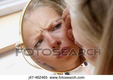 21 year old girl looking in the mirror plucking her eyebrows, scowling View Large Photo Image Stock Photography - 21 year old girl looking in the mirror plucking her eyebrows, scowling. Fotosearch