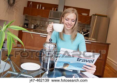 21 year old girl sitting at the kitchen table reading the paper, drinking coffee View Large Photo Image Stock Photo - 21 year old girl sitting at the kitchen table reading the paper, drinking coffee. Fotosearch