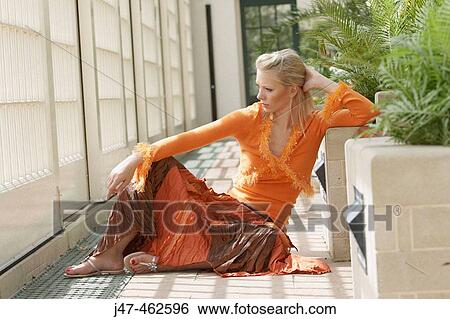 Stock Photograph - 21 year old girl sitting on the floor, looking off camera. Fotosearch