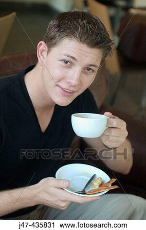 22 year old boy sitting in a bar drinking a cup of coffee, smiling into camera View Large Photo Image Stock Image - 22 year old boy sitting in a bar drinking a cup of coffee, smiling into camera. Fotosearch