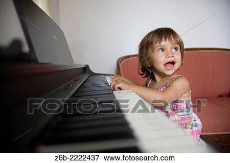 Stock Photo - 23 months old baby girl playing piano.. Fotosearch