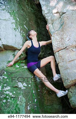 23 year old brunette woman dressed in exercise clothing perched in an opening in a rock wall View Large Photo Image Picture - 23 year old brunette woman dressed in exercise clothing perched in an opening in a rock wall. Fotosearch