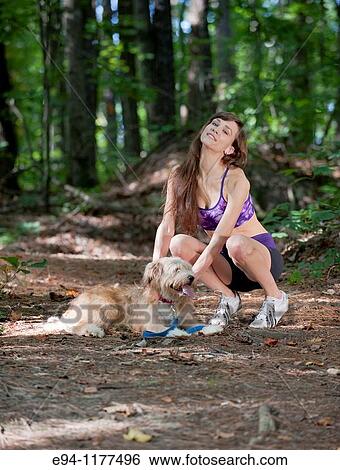 23 year old brunette woman dressed in exercise clothing walking her dog through a forest View Large Photo Image Stock Photograph - 23 year old brunette woman dressed in exercise clothing walking her dog through a forest. Fotosearch
