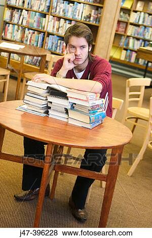 24 year old man leaning over a pile of books, head in hand, in the library View Large Photo Image Stock Photo - 24 year old man leaning over a pile of books, head in hand, in the library. Fotosearch