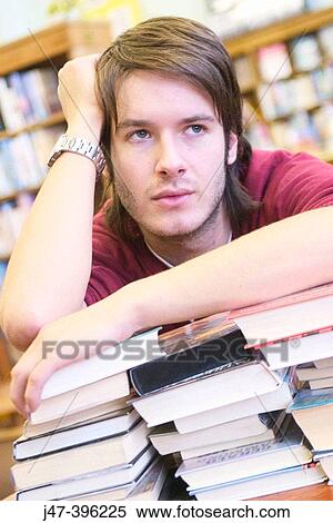 24 year old man leaning over a pile of books, head in hand, in the library View Large Photo Image Stock Photography - 24 year old man leaning over a pile of books, head in hand, in the library. Fotosearch