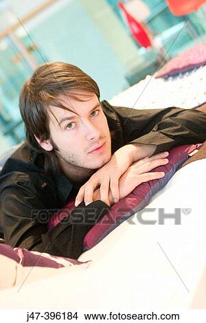 24 year old man lying on bed, serious, looking into camera View Large Photo Image Picture - 24 year old man lying on bed, serious, looking into camera. Fotosearch