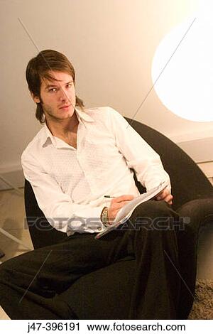 24 year old man sitting in chair writing looking into camera View Large Photo Image Stock Image - 24 year old man sitting in chair writing looking into camera. Fotosearch