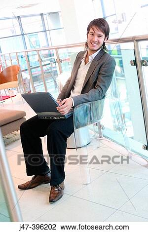 24 year old man sitting in chair, smiling into camera, working on laptop View Large Photo Image Stock Image - 24 year old man sitting in chair, smiling into camera, working on laptop. Fotosearch