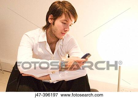 24 year old man sitting in chair texting a message on mobile phone View Large Photo Image Stock Photo - 24 year old man sitting in chair texting a message on mobile phone. Fotosearch
