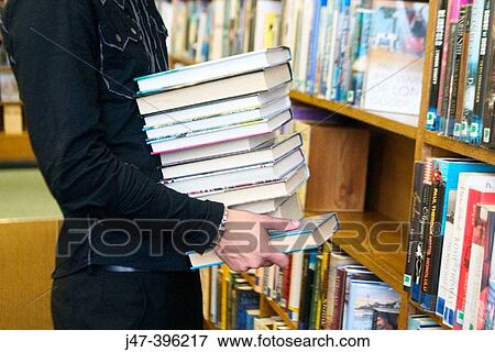 24 year old man standing, holding a pile of books, in the library View Large Photo Image Stock Photo - 24 year old man standing, holding a pile of books, in the library. Fotosearch