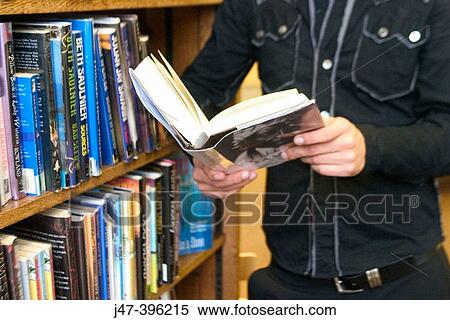 24 year old man standing, holding a book, in the library View Large Photo Image Stock Photography - 24 year old man standing, holding a book, in the library. Fotosearch