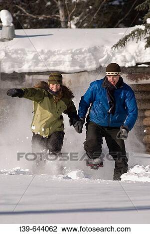 25- 35 year old couple running in the snow on snowshoes with log cabin in background. Teslin River, Yukon Territory Canada. View Large Photo Image Stock Image - 25- 35 year old couple running in the snow on snowshoes with log cabin in background. Teslin River, Yukon Territory Canada.. Fotosearch