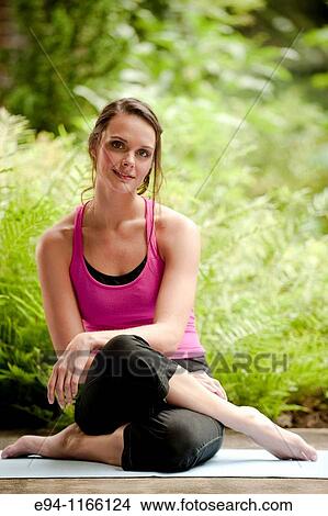 25 year old brunette woman in a garden settng wearing work out clothing, sitting on the ground smiling at the camera. View Large Photo Image Picture - 25 year old brunette woman in a garden settng wearing work out clothing, sitting on the ground smiling at the camera.. Fotosearch