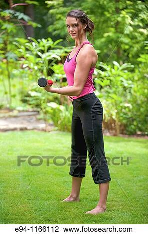25 year old brunette woman in a garden settng wearing work out clothing with dumbbells View Large Photo Image Stock Image - 25 year old brunette woman in a garden settng wearing work out clothing with dumbbells. Fotosearch