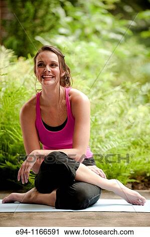 25 year old brunette woman in a garden settng wearing work out clothing, sitting on the ground smiling at the camera. View Large Photo Image Stock Image - 25 year old brunette woman in a garden settng wearing work out clothing, sitting on the ground smiling at the camera.. Fotosearch
