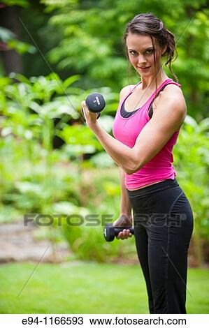 25 year old brunette woman in a garden settng wearing work out clothing with dumbbells View Large Photo Image Stock Image - 25 year old brunette woman in a garden settng wearing work out clothing with dumbbells. Fotosearch