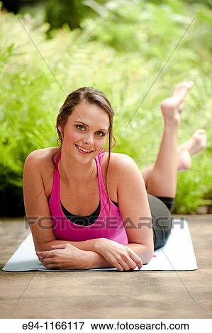 Stock Photo - 25 year old brunette woman in a garden settng wearing work out clothing, stretching and exercising. Fotosearch