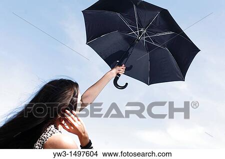 25 year old woman outdoors with umbrella against sky View Large Photo Image Picture - 25 year old woman outdoors with umbrella against sky. Fotosearch