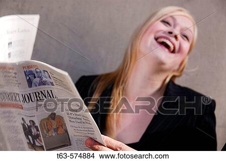25 yr old caucasian business woman laughing while holding business news paper View Large Photo Image Picture - 25 yr old caucasian business woman laughing while holding business news paper. Fotosearch