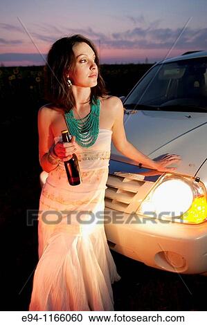 26 year old brunette woman wearing a white dress on a country road holding a beer bottle at dusk View Large Photo Image Stock Image - 26 year old brunette woman wearing a white dress on a country road holding a beer bottle at dusk. Fotosearch