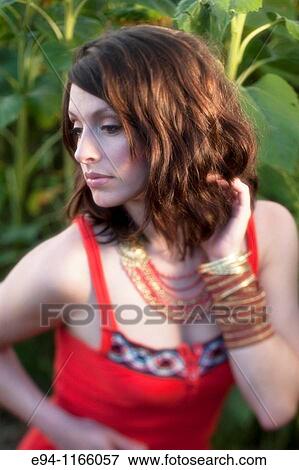 Stock Photo - 26 year old brunette woman wearing a red dress in a field of sunflowers. Fotosearch