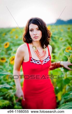 Stock Photography - 26 year old brunette woman wearing a red dress in a field of sunflowers. Fotosearch
