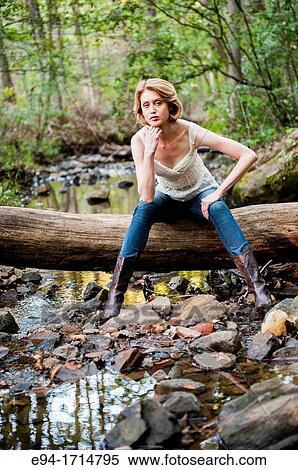 29 year old blond woman in a forest sitting a on log wearing blue jeans and a white top View Large Photo Image Stock Photography - 29 year old blond woman in a forest sitting a on log wearing blue jeans and a white top. Fotosearch
