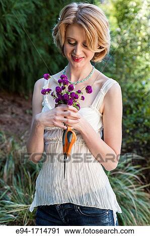 29 year old blond woman in a garden setting holding a small bouquet of Gomphrena flowers View Large Photo Image Stock Image - 29 year old blond woman in a garden setting holding a small bouquet of Gomphrena flowers. Fotosearch