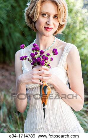 29 year old blond woman in a garden setting holding a small bouquet of Gomphrena flowers View Large Photo Image Stock Photo - 29 year old blond woman in a garden setting holding a small bouquet of Gomphrena flowers. Fotosearch