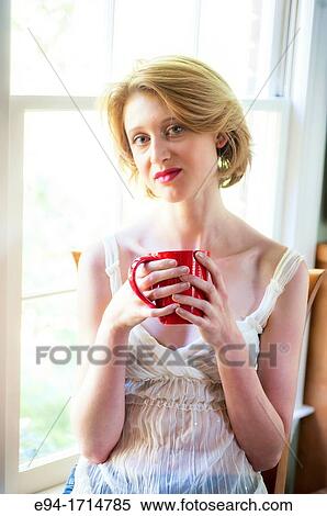 29 year old blond woman looking at the camera sitting by a window holding a red cup View Large Photo Image Stock Photography - 29 year old blond woman looking at the camera sitting by a window holding a red cup. Fotosearch