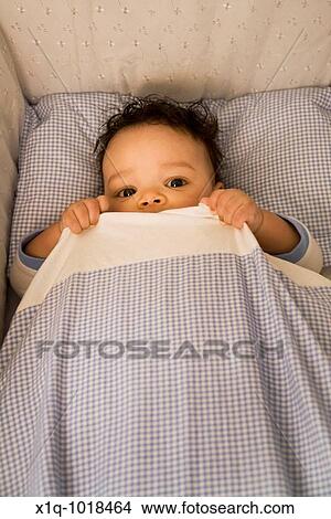3 1/2 months old boy lying in his bed and hiding under his duvet View Large Photo Image Picture - 3 1/2 months old boy lying in his bed and hiding under his duvet. Fotosearch
