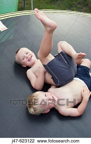 3 and 5 year old boys lying on their backs on a trampoline, laughing into camera View Large Photo Image Stock Image - 3 and 5 year old boys lying on their backs on a trampoline, laughing into camera. Fotosearch
