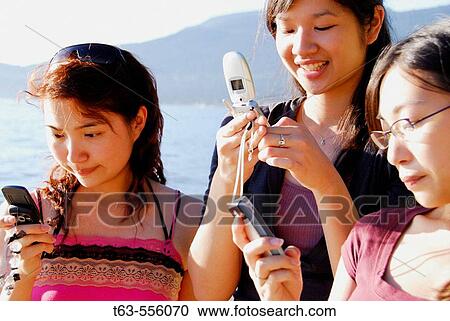 3 asian women each using cell phones View Large Photo Image Stock Image - 3 asian women each using cell phones. Fotosearch