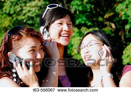 Stock Photo - 3 asian women each using cell phones. Fotosearch