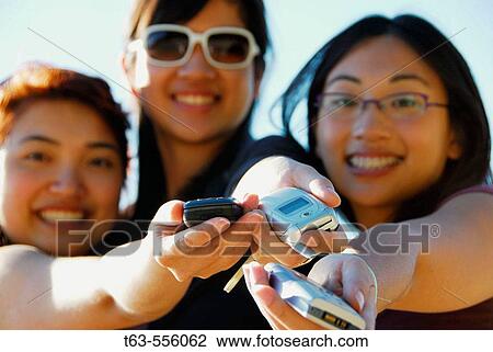 3 asian women holding cell phones out in hands View Large Photo Image Stock Image - 3 asian women holding cell phones out in hands. Fotosearch