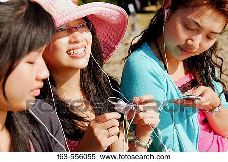 3 asian women sitting on beach together using music devices with earphones View Large Photo Image Stock Photography - 3 asian women sitting on beach together using music devices with earphones. Fotosearch