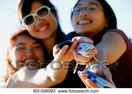 3 asian women standing holding cell phones out in hands View Large Photo Image Stock Image - 3 asian women standing holding cell phones out in hands. Fotosearch