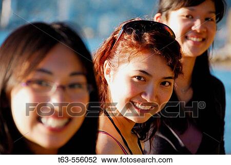 Stock Image - 3 asian women standing on beach together. Fotosearch