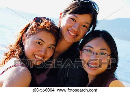 Picture - 3 asian women standing together on beach. Fotosearch