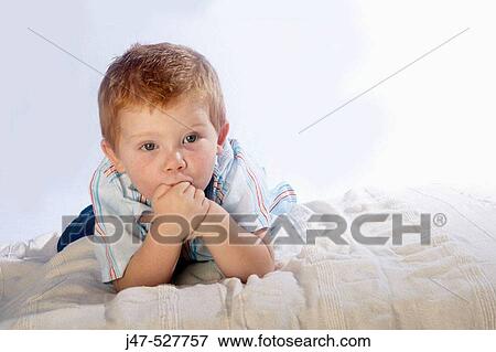 3 year old boy looking into camera lying on his tummy, with his hands up to his face looking curious View Large Photo Image Stock Photo - 3 year old boy looking into camera lying on his tummy, with his hands up to his face looking curious. Fotosearch