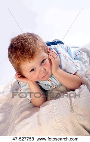 3 year old boy looking into camera lying on his tummy, with his hands up to his face looking fedup View Large Photo Image Stock Photo - 3 year old boy looking into camera lying on his tummy, with his hands up to his face looking fedup. Fotosearch