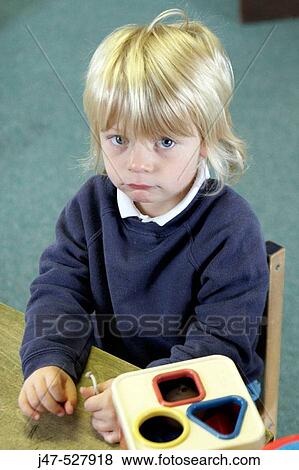 3 year old boy, looking into camera, playing at the desk at nursery, looking serious View Large Photo Image Stock Photo - 3 year old boy, looking into camera, playing at the desk at nursery, looking serious. Fotosearch