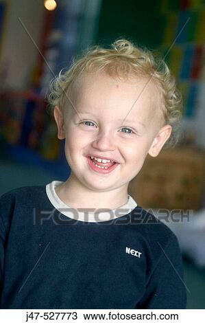 Stock Image - 3 year old boy smiling into camera at nursery. Fotosearch