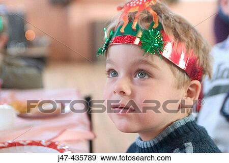Stock Photo - 3 year old boyl at a party wearing a party hat looking off camera, smiling. Fotosearch