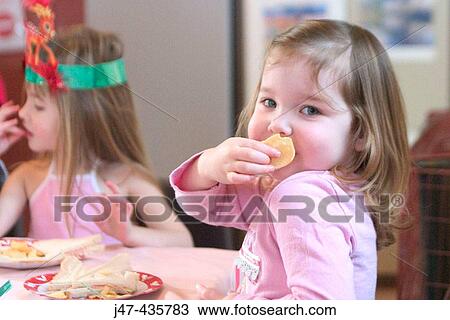 3 year old girl at a party eating a biscuit smiling cheekily into camera View Large Photo Image Stock Image - 3 year old girl at a party eating a biscuit smiling cheekily into camera. Fotosearch
