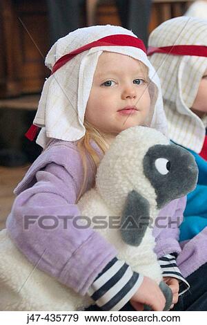 Stock Photo - 3 year old girl dressed up for a nativity play holding a toy sheep, looking into camera. Fotosearch
