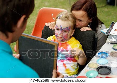 3 year old girl having her face painted, looking at it in the mirror, smiling, her mother crouching behind her View Large Photo Image Stock Photo - 3 year old girl having her face painted, looking at it in the mirror, smiling, her mother crouching behind her. Fotosearch