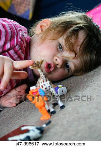 3 year old girl lying down on the floor playing with toy animals View Large Photo Image Stock Photo - 3 year old girl lying down on the floor playing with toy animals. Fotosearch
